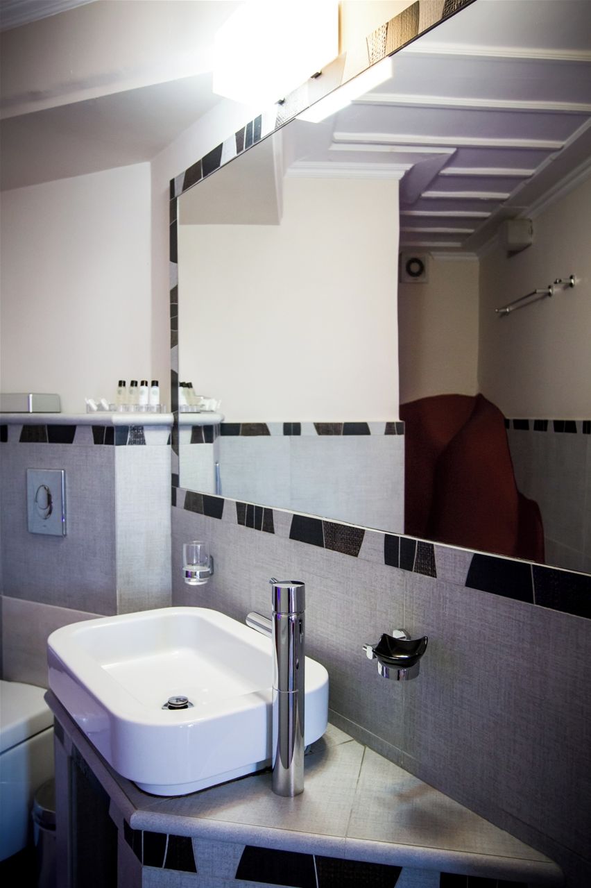 Ein Badezimmer mit weißem Waschbecken, einem Spiegel und einem Handtuchhalter.