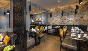 A restaurant with a modern interior, featuring a map wall, black pendant lights, and a variety of seating options including booths and tables. - Hôtel International Paris (Paris)