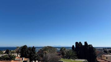 Paisaje costero con edificios históricos, cielo azul despejado y vista al mar.