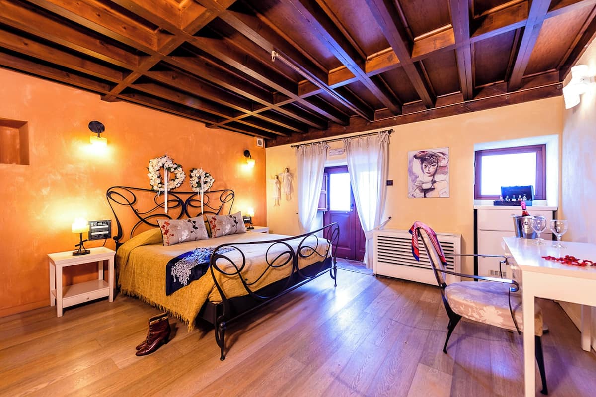 A bedroom with a bed, bedside table, chair, and a desk with a chair.