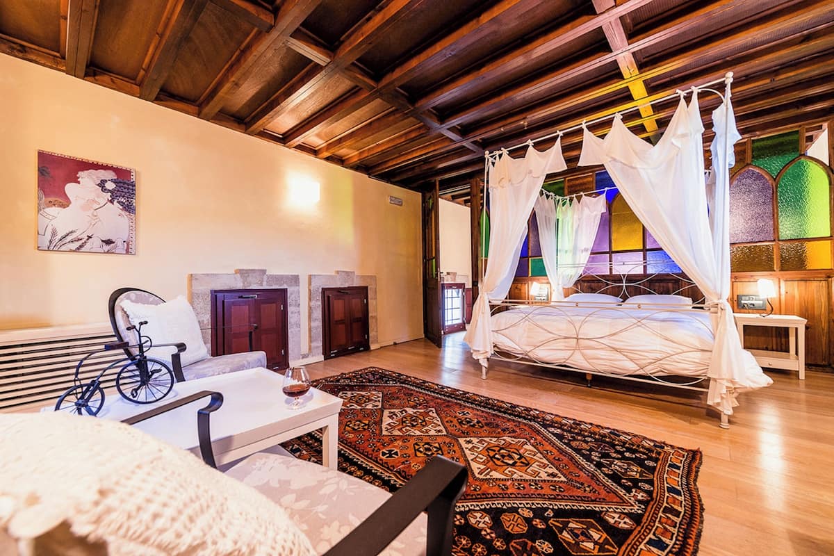 A room with a four-poster bed, a bicycle, a table, and a large patterned rug.