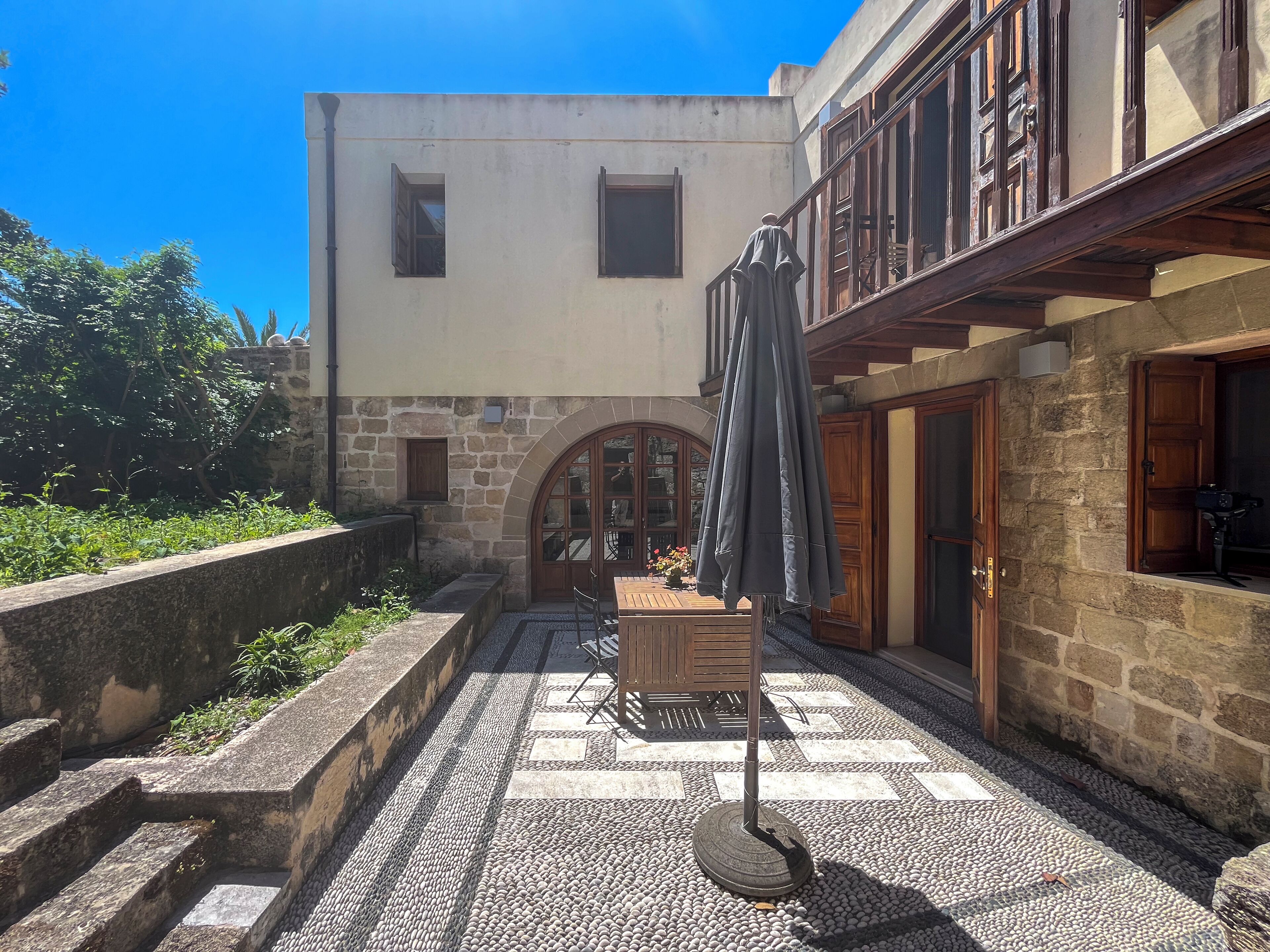 A courtyard with stone steps, a wooden table, and an umbrella.