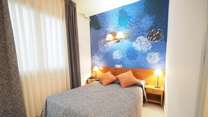 Ein Schlafzimmer mit einem Bett, zwei Nachttischlampen, einem Nachttisch und einem großen abstrakten Gemälde an der Wand.