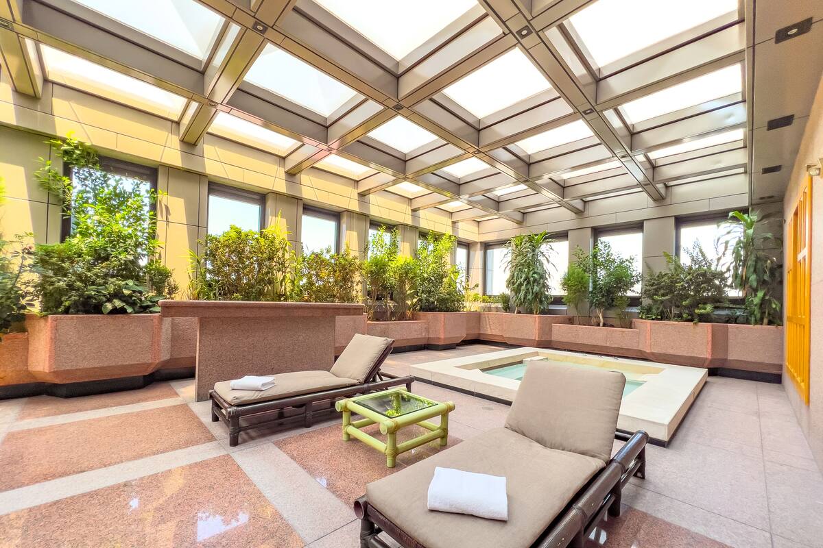 A modern indoor lounge area with seating, a pool, and greenery.