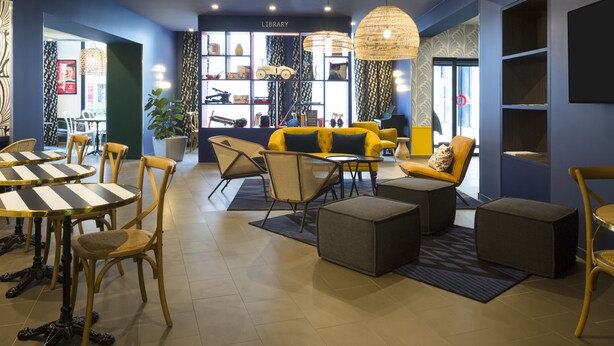 A modern lounge area with a library, comfortable seating, and a large window.