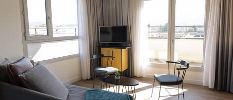 Una sala de estar moderna con un sofá, un televisor, una mesita y dos sillones.