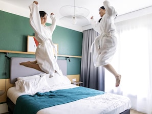 A hotel room with a bed, a bedside table, a wall-mounted fan, and a window with curtains. - Aparthotel Adagio Annecy Centre (Annecy)