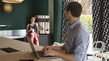 Une cuisine moderne avec des appareils en acier inoxydable, un ordinateur portable sur une table et une personne qui travaille.