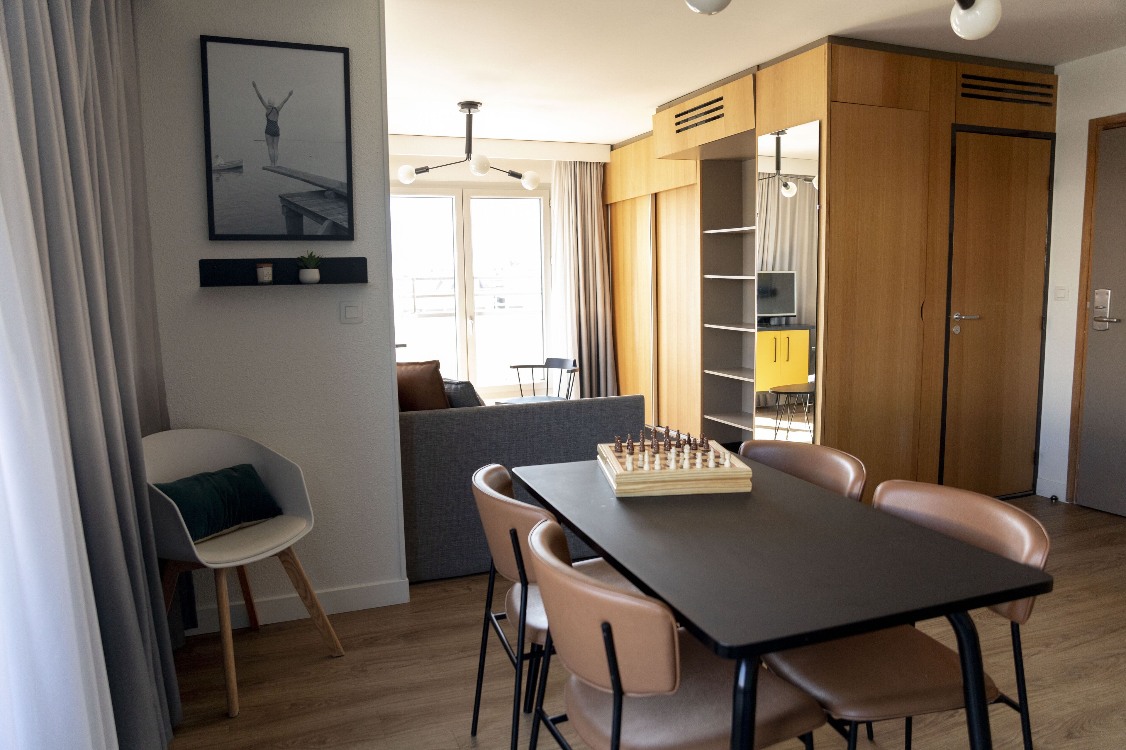 Een moderne eetruimte met een schaakbord, houten kasten en een bank.