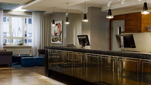A modern reception area with a counter, seating, and artwork. - Radisson Blu Aleksanteri Hotel, Helsinki (Helsinki)