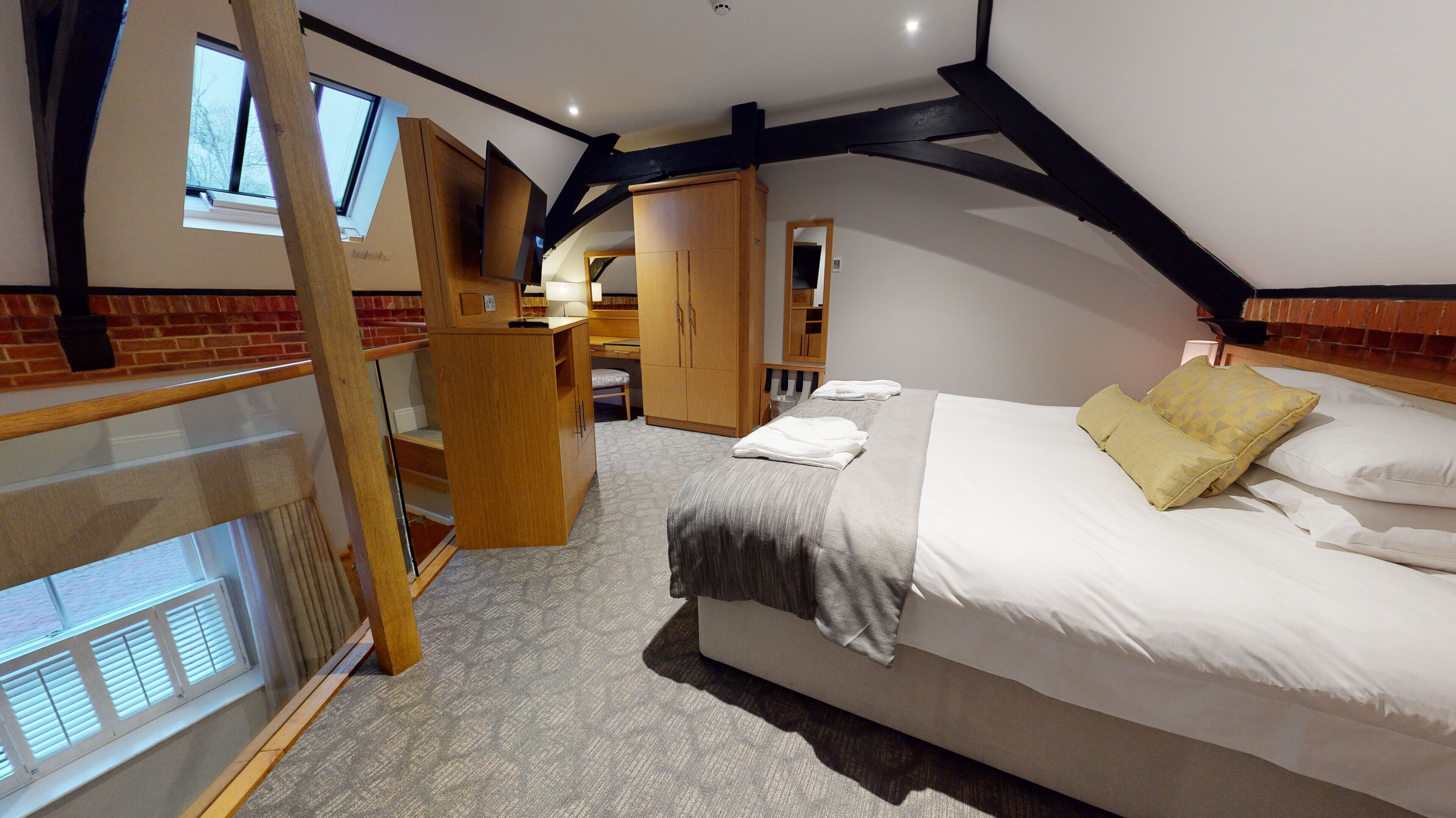 A bedroom with a bed, a desk, and a chair. There is a window and a door leading to another room.