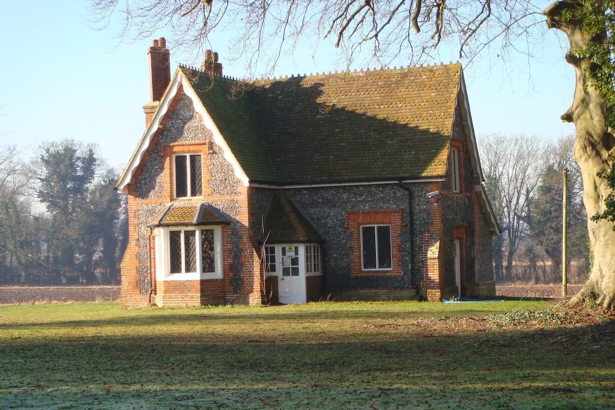 A traditional brick house with a steeply pitched roof, a small porch, and a visible chimney.