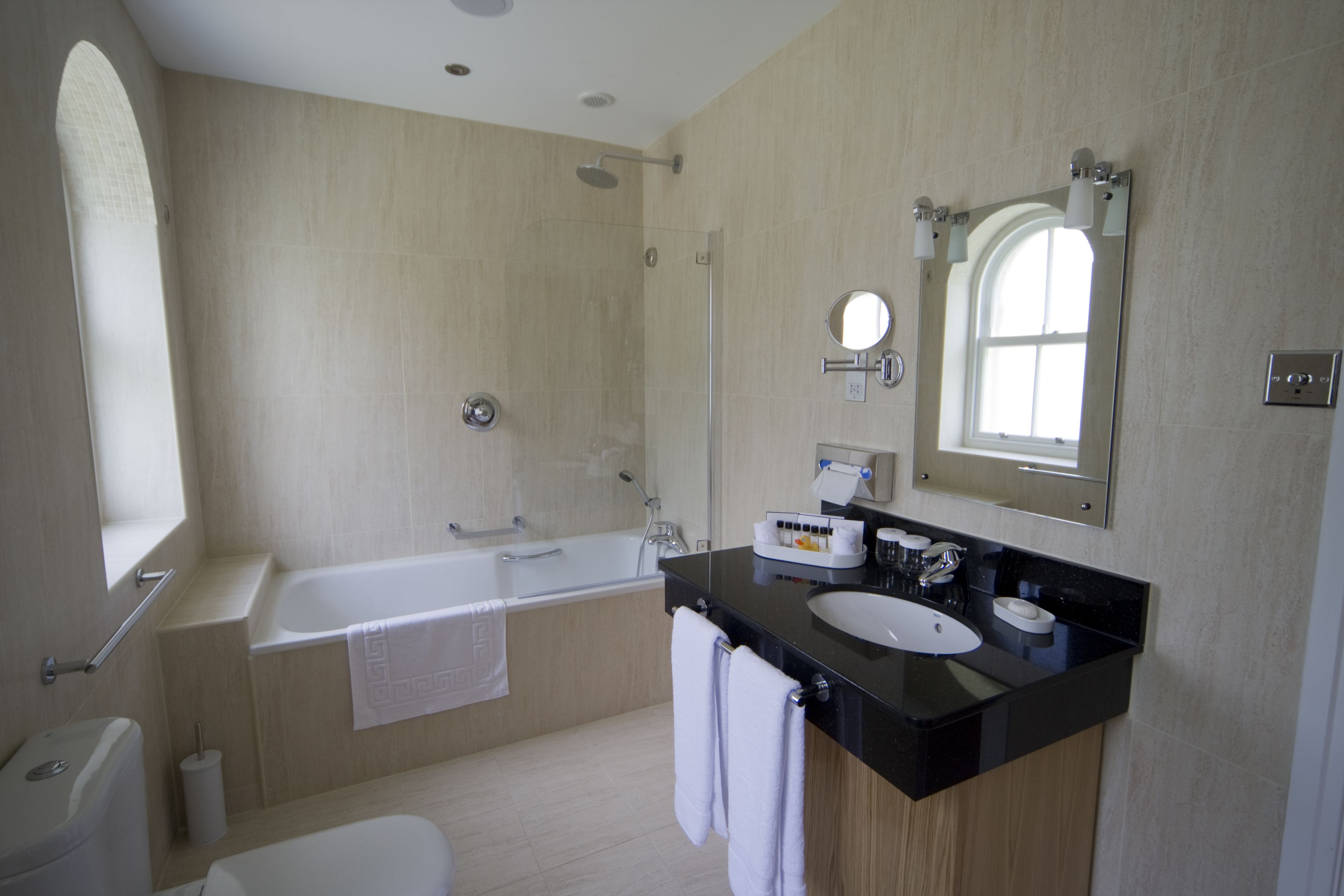 A modern bathroom with a bathtub, a sink, and a large mirror.