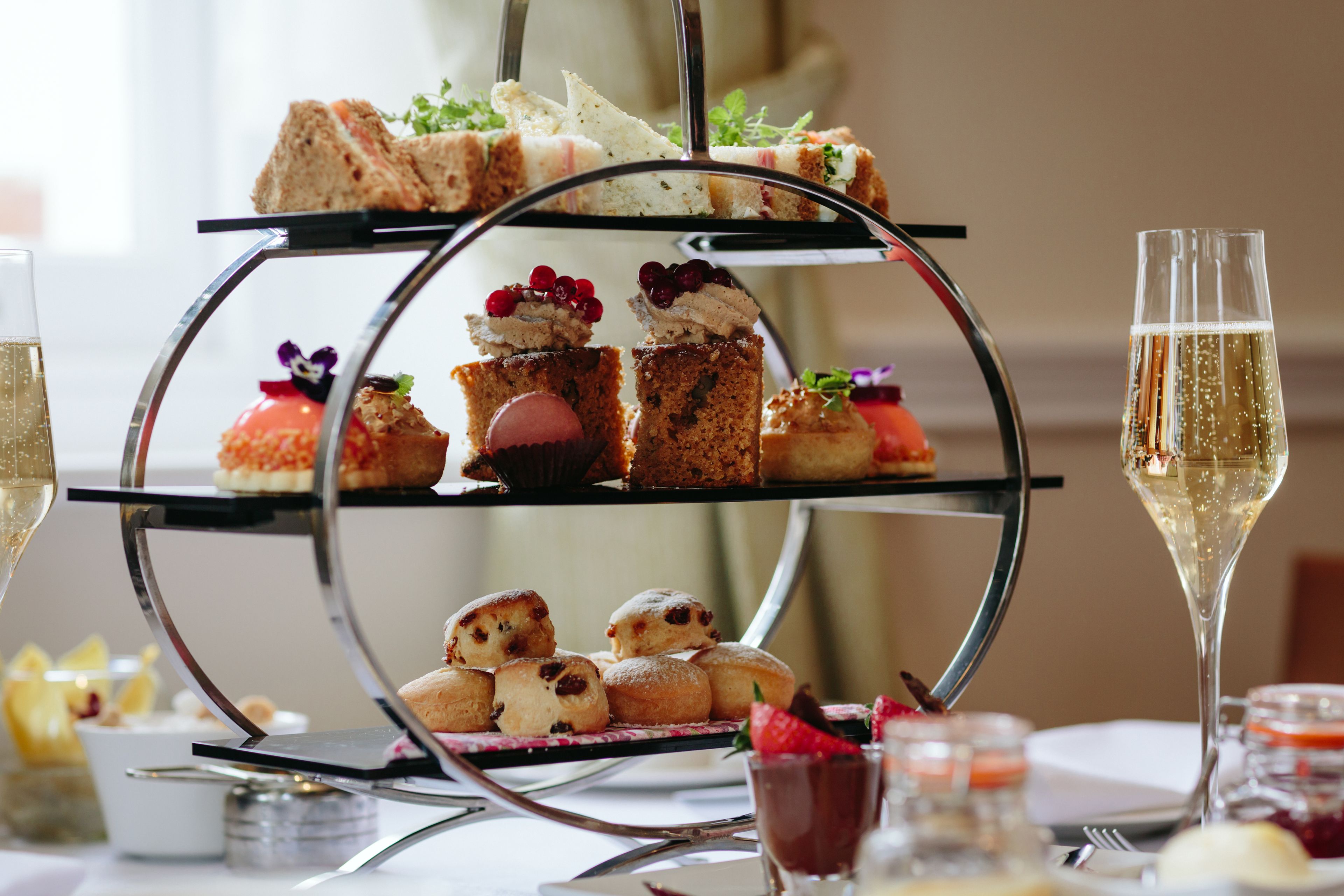 A three-tiered dessert stand with various pastries and a glass of champagne.