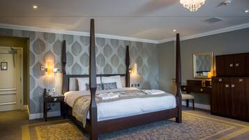 A four-poster bed with a canopy, bedside lamps, a large mirror, and a wardrobe in a hotel room.