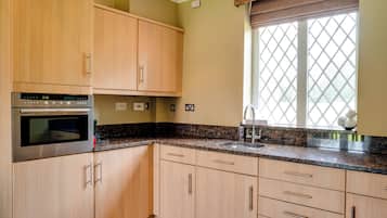 A kitchen with wooden cabinets, a built-in oven, granite countertops, and a window with a grid pattern.