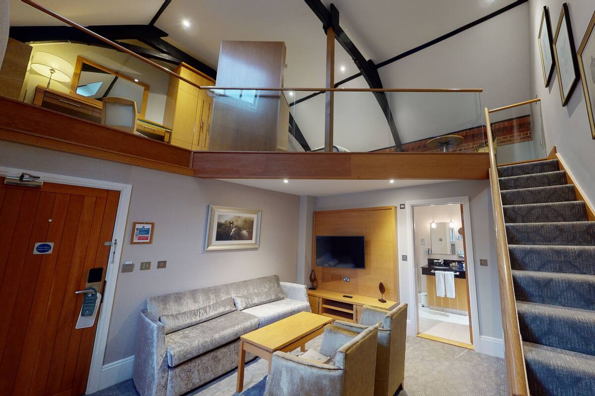 A spacious living area with a sofa, coffee table, and a staircase leading to an upper level.