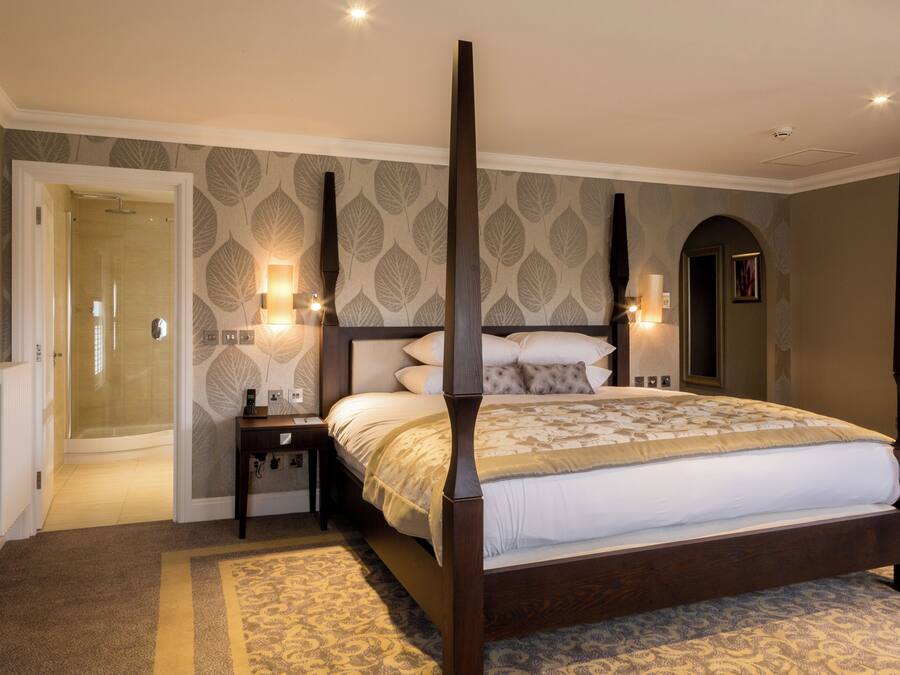 A four-poster bed with a wooden frame, a bedside table, and a nightstand.