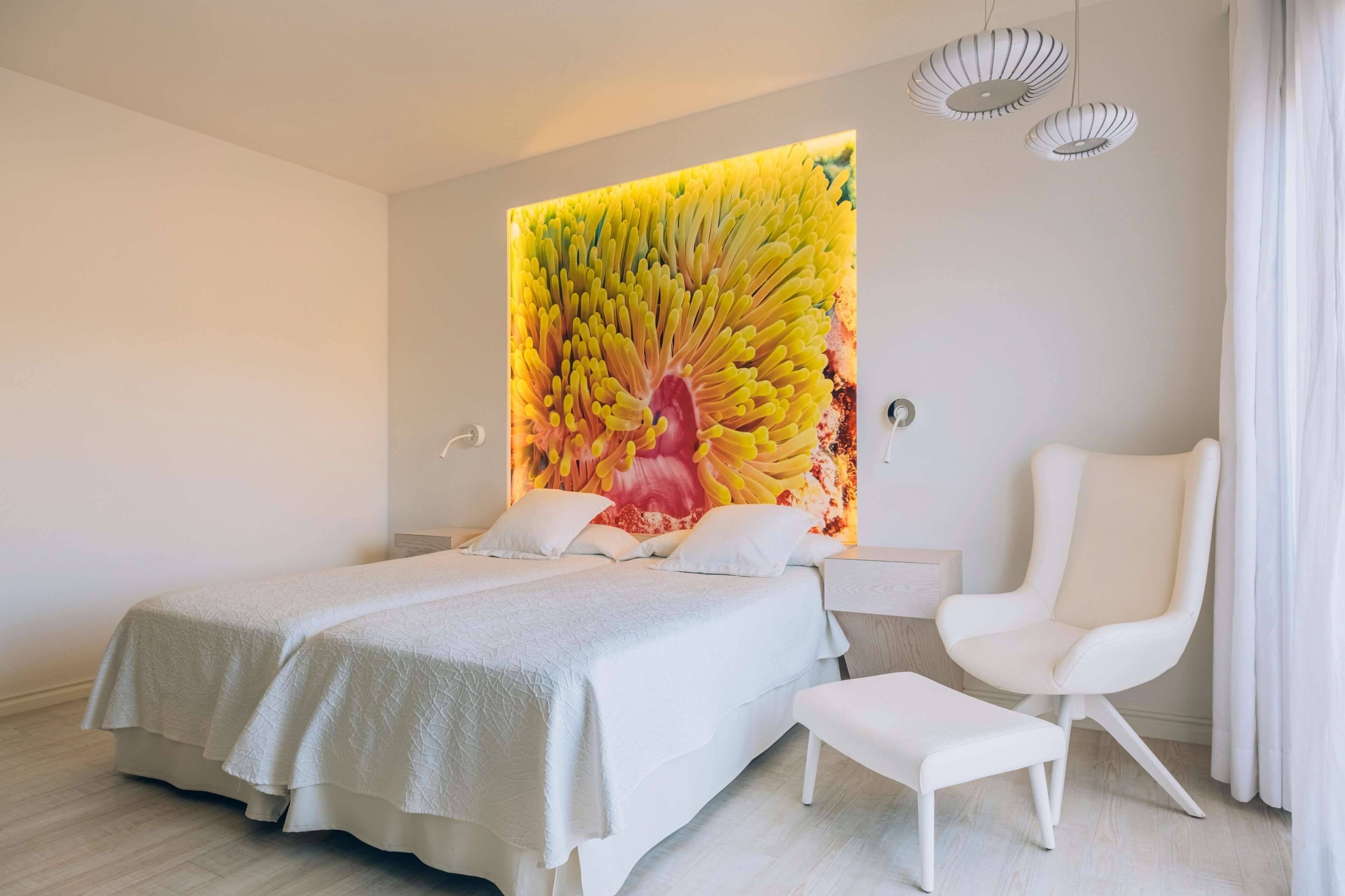 A modern bedroom with a large bed, a white chair, and a unique wall mural.