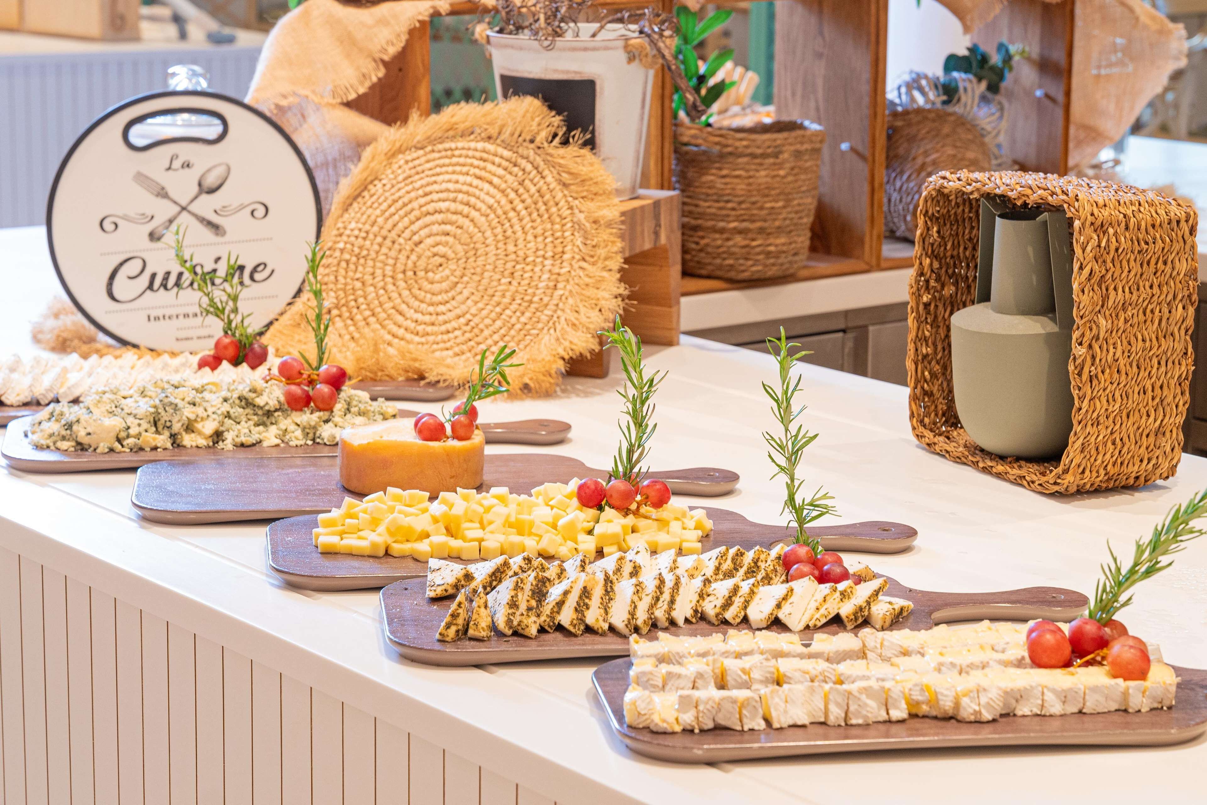 A buffet table with various cheeses, fruits, and garnishes.