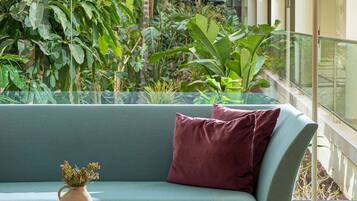 Un espacio interior moderno con un sofá azul verdoso, una mesa de centro de madera y una planta en maceta.