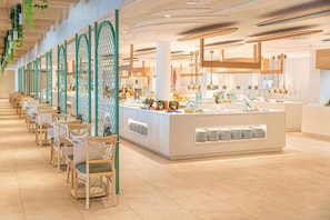 A modern dining area with a long counter, chairs, and a buffet station. - Iberostar Waves Gaviotas Park -All Inclusive (Pajara)