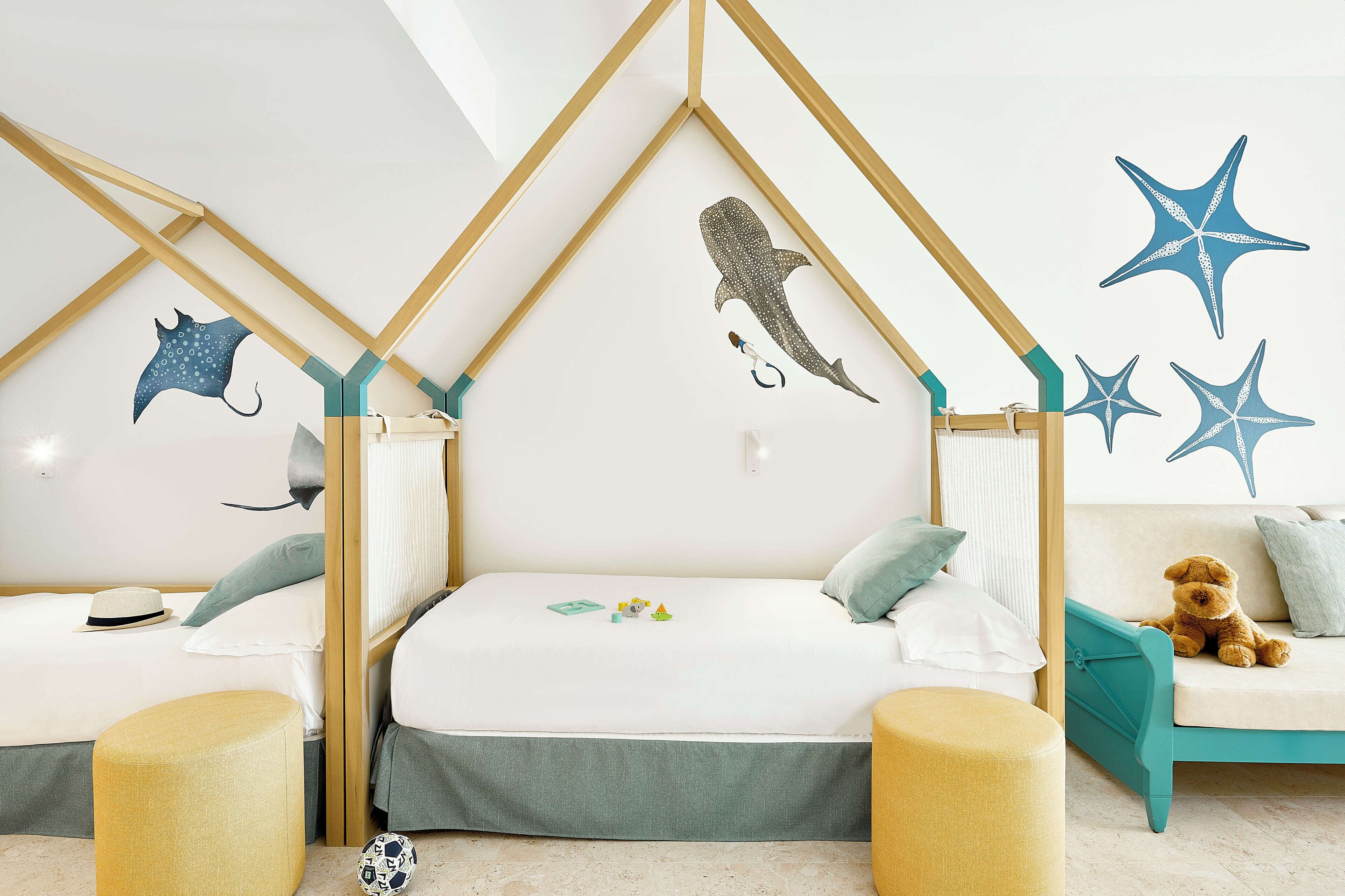 Ein Zimmer mit zwei Betten, einem Schlafsofa und einer Wand mit Sternfisch- und Hai-Motiven.