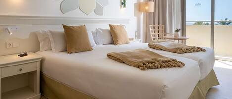 Habitación de hotel con una cama grande, una mesita de noche, una silla, una pequeña mesa con una planta y vistas al exterior.