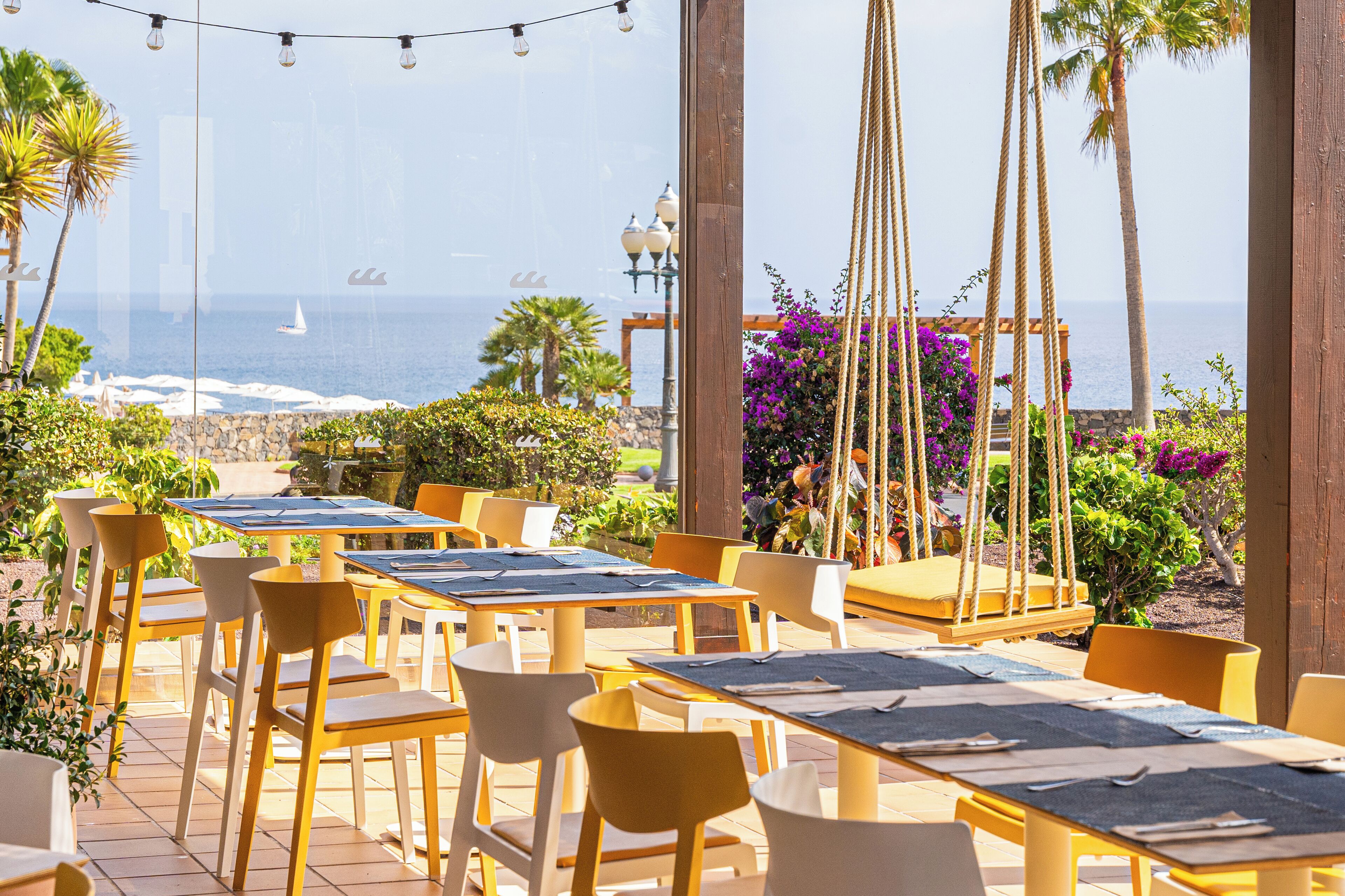 An outdoor dining area with tables and chairs, overlooking the ocean.
