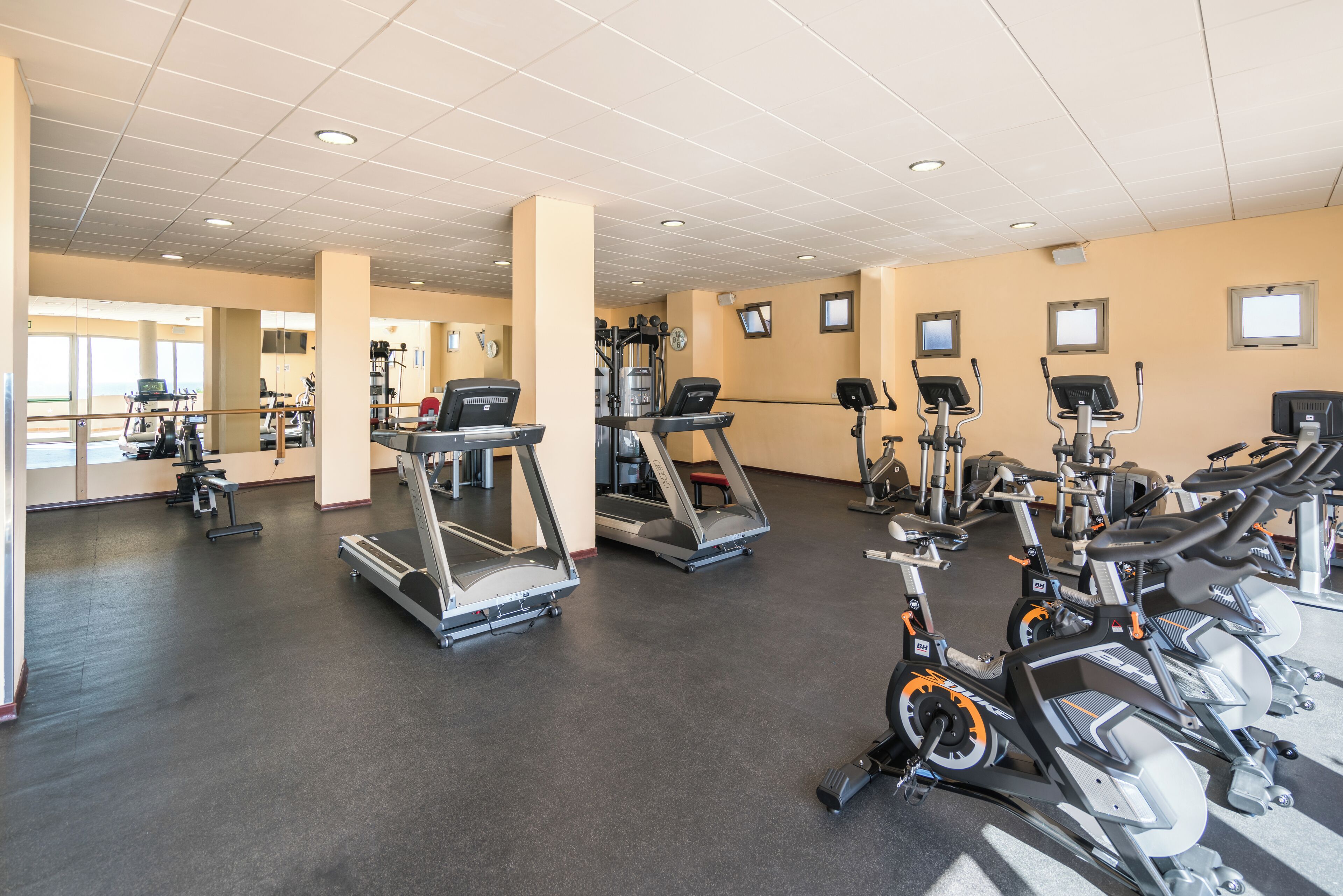 Une salle de sport équipée de tapis de course, de vélos elliptiques et d'appareils de musculation.