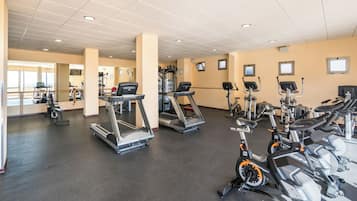 Une salle de sport équipée de tapis de course, de vélos elliptiques et d'appareils de musculation.