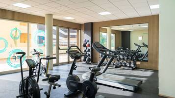 A gym with stationary bikes, treadmills, and dumbbells.