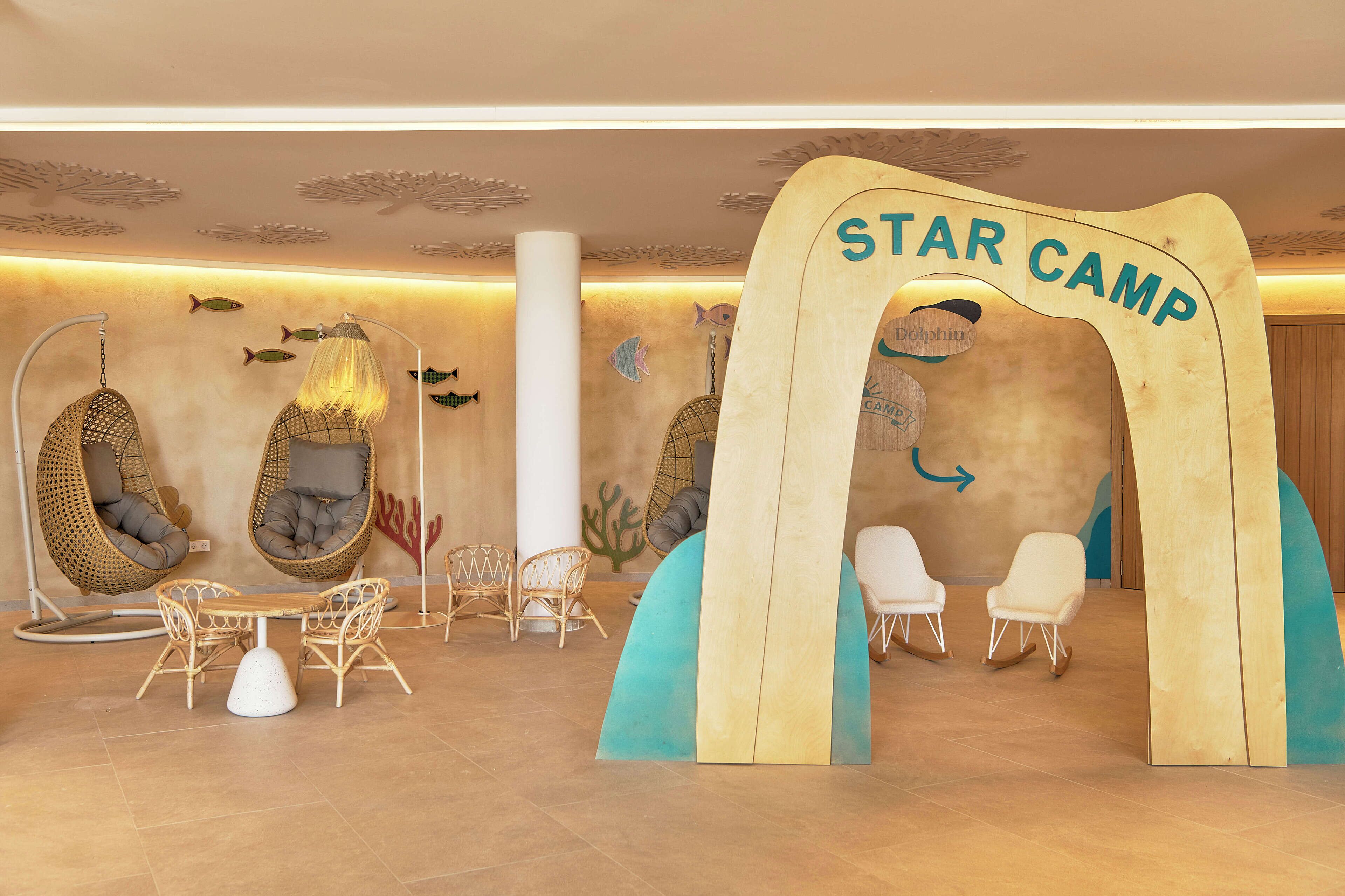 Een receptiegebied van Star Camp met hangstoelen, een toegangspartij in de vorm van een surfplank en een muur versierd met vissen en koraal.