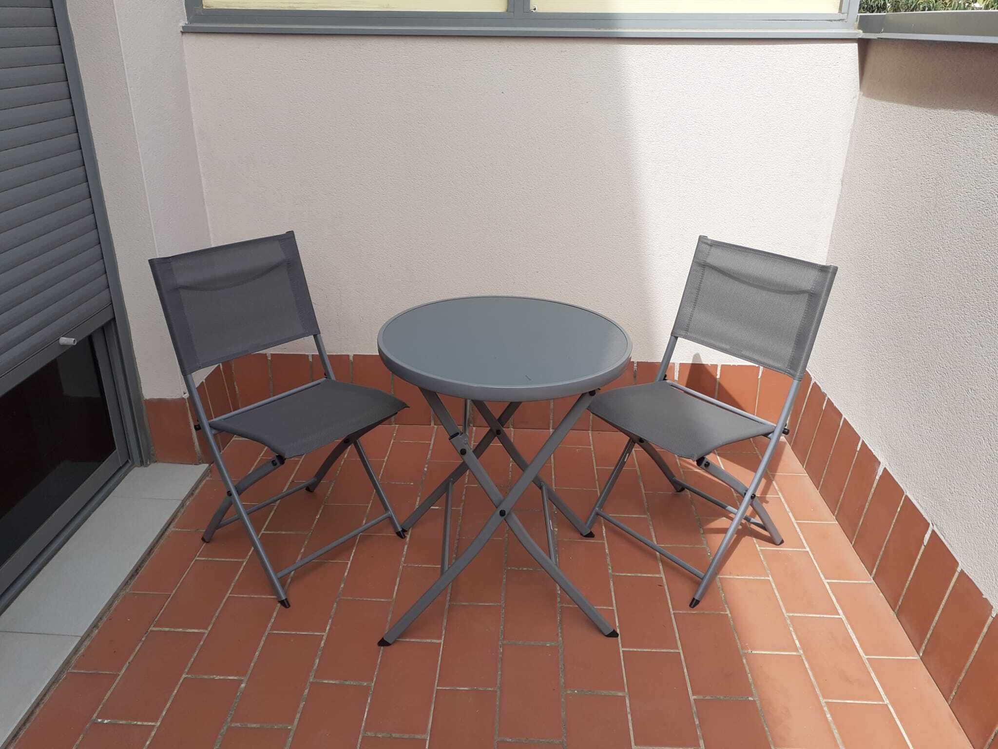 A small outdoor patio with a round table and two chairs.