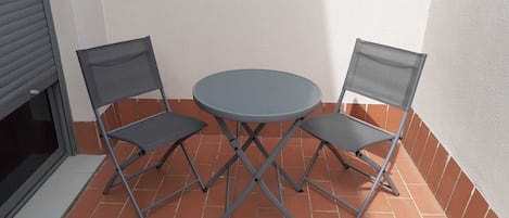 A small outdoor patio with a round table and two chairs.