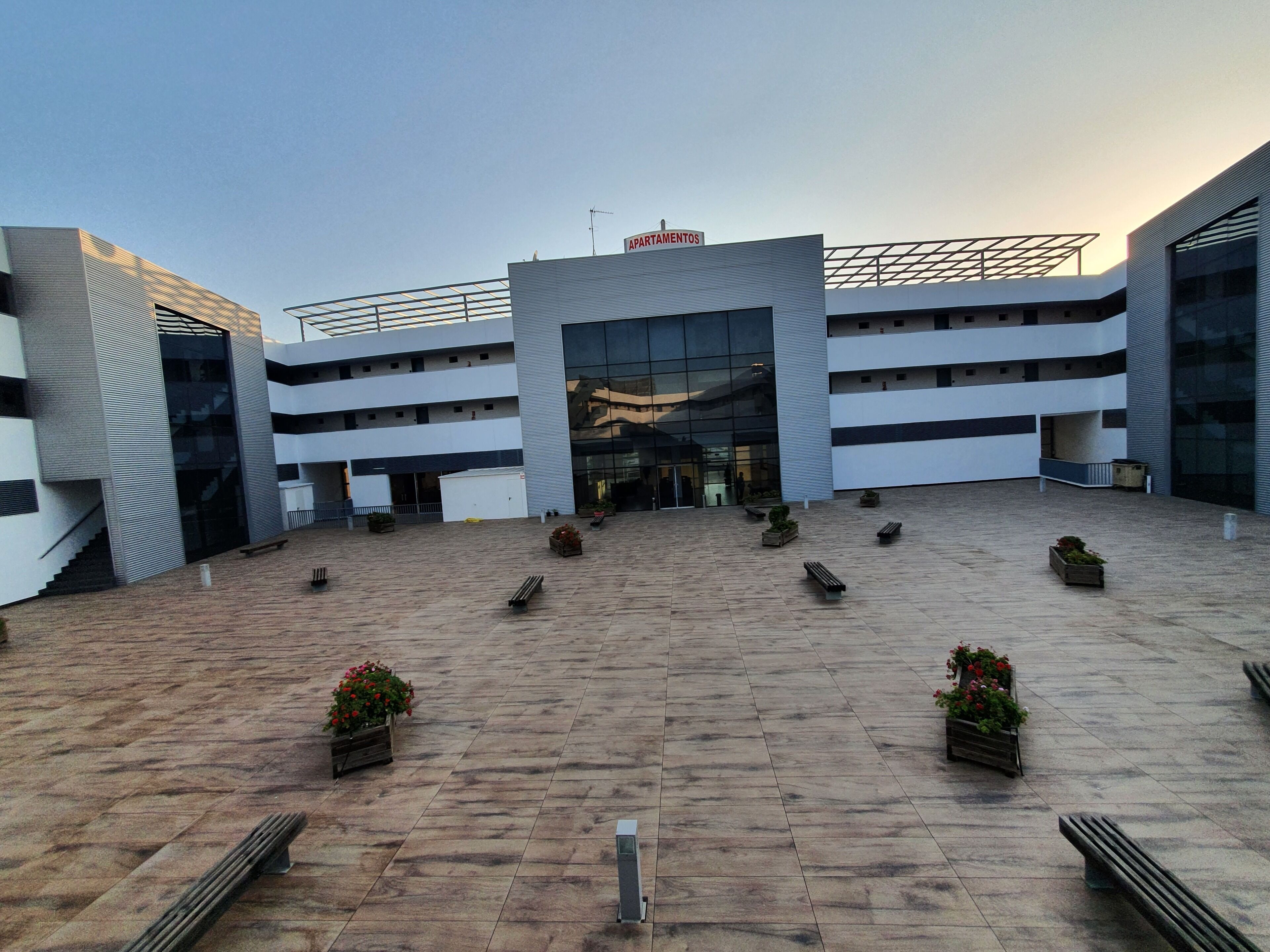 A modern building with a central entrance, multiple floors, and a flat roof.