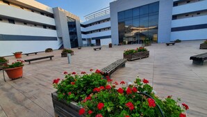 Un edificio moderno con varios pisos, zonas de estar al aire libre y plantas en macetas.