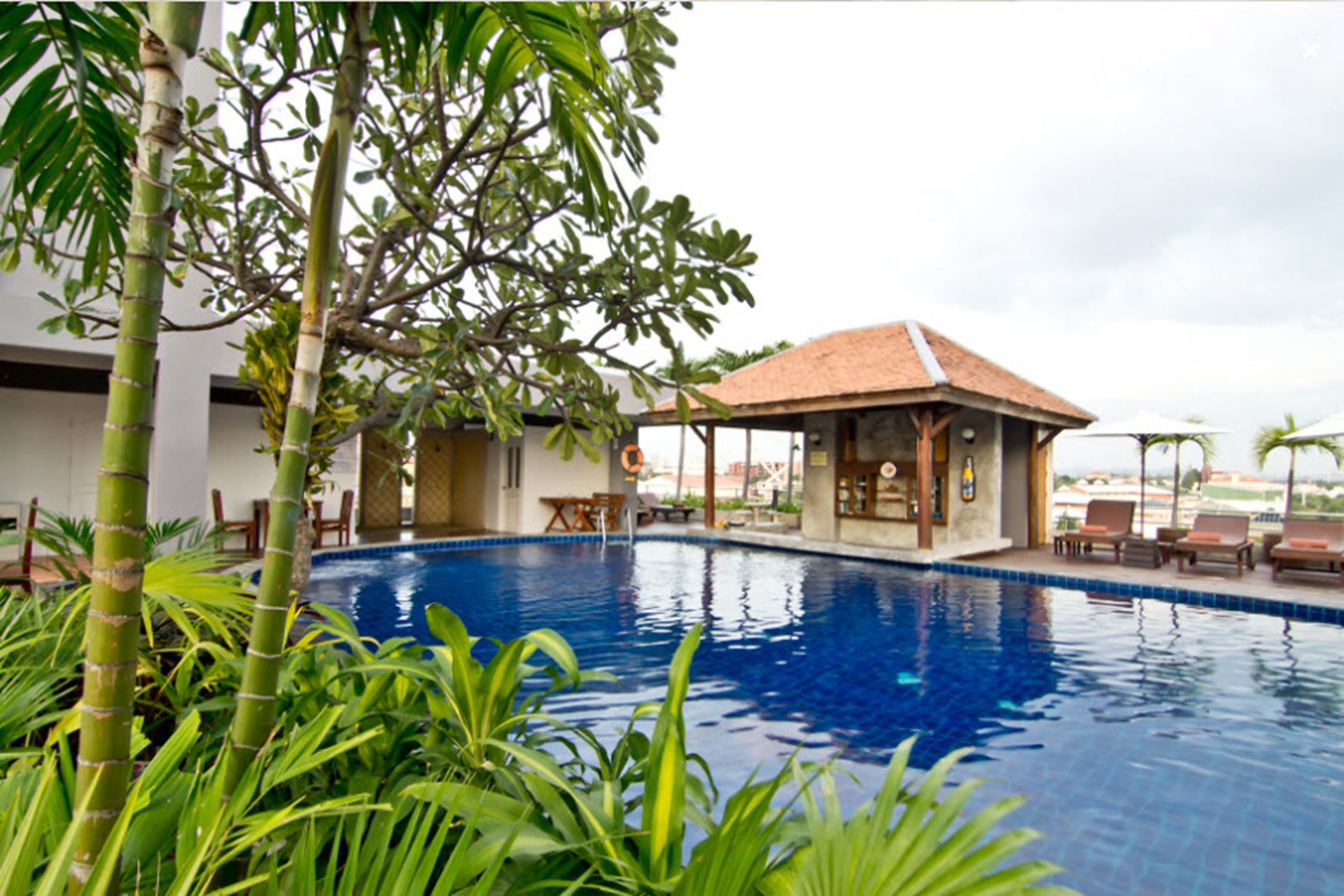 A swimming pool with surrounding lounge chairs and a small pavilion.