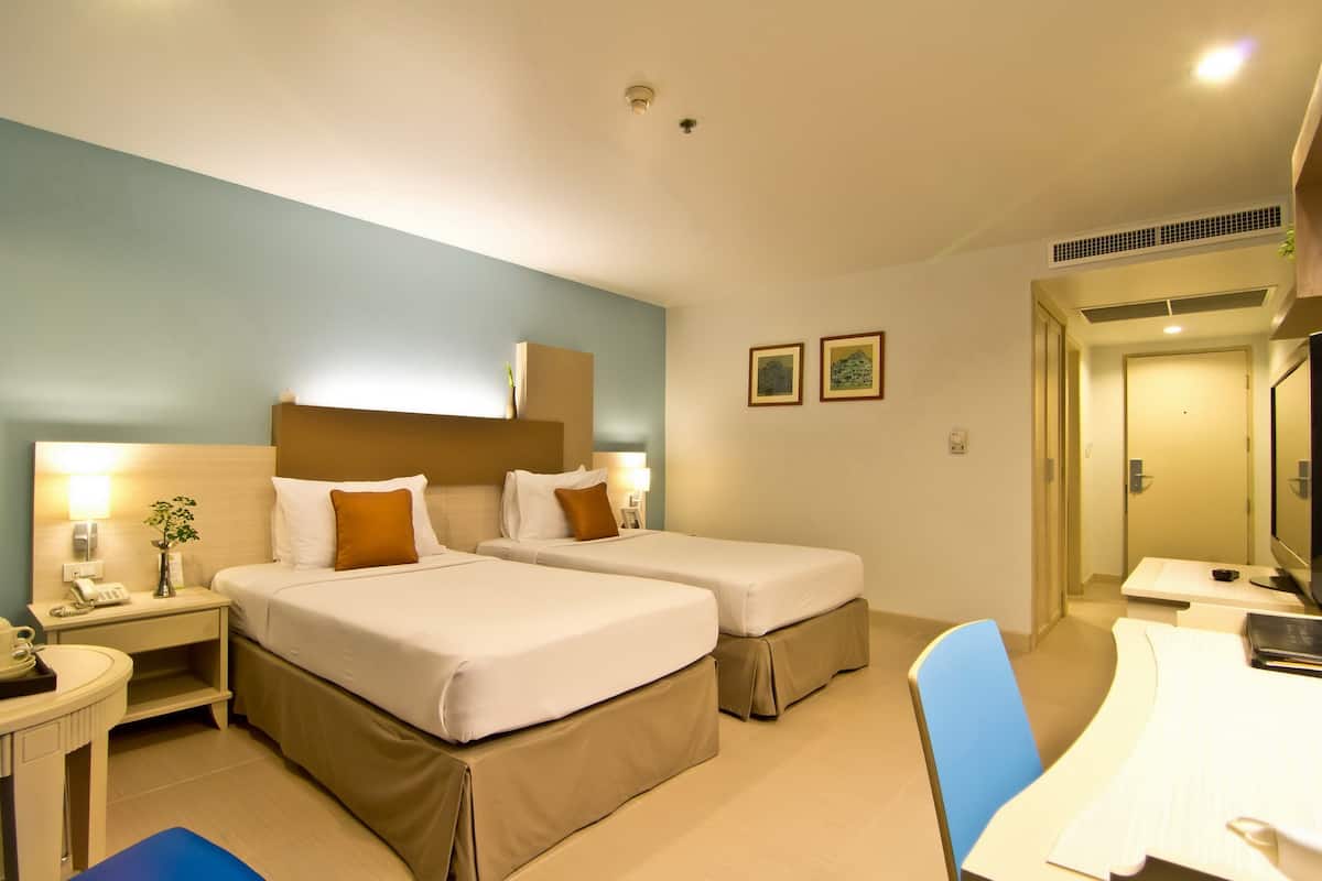 Ein Hotelzimmer mit zwei Betten, einem Schreibtisch und einem Stuhl.