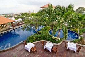 Een buitenzwembad, parasols bij het zwembad en ligstoelen