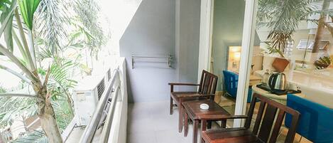 A balcony with a dining table and chairs, a blue sofa, and a potted plant.
