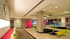 A modern lobby with a red wall, a seating area with yellow chairs, and a large pillar. - SUNSHINE VISTA (Pattaya)