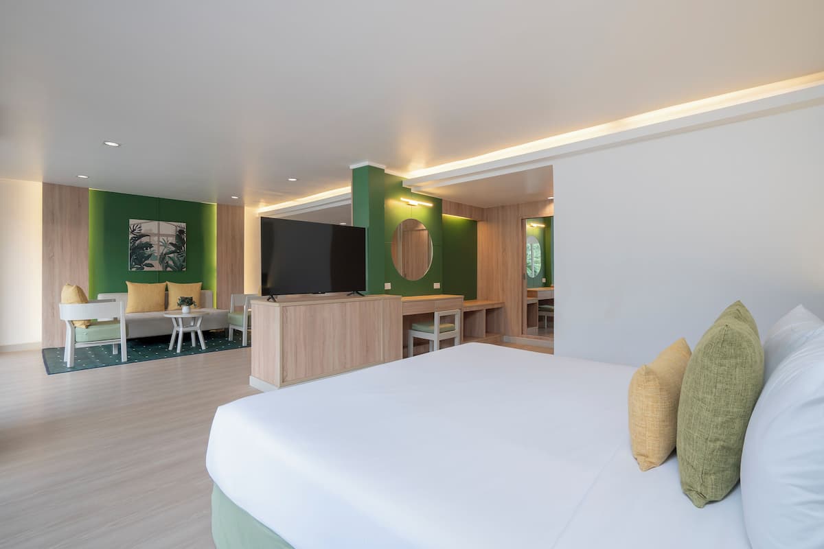 A modern hotel room with a large bed, a desk, a chair, and a TV.