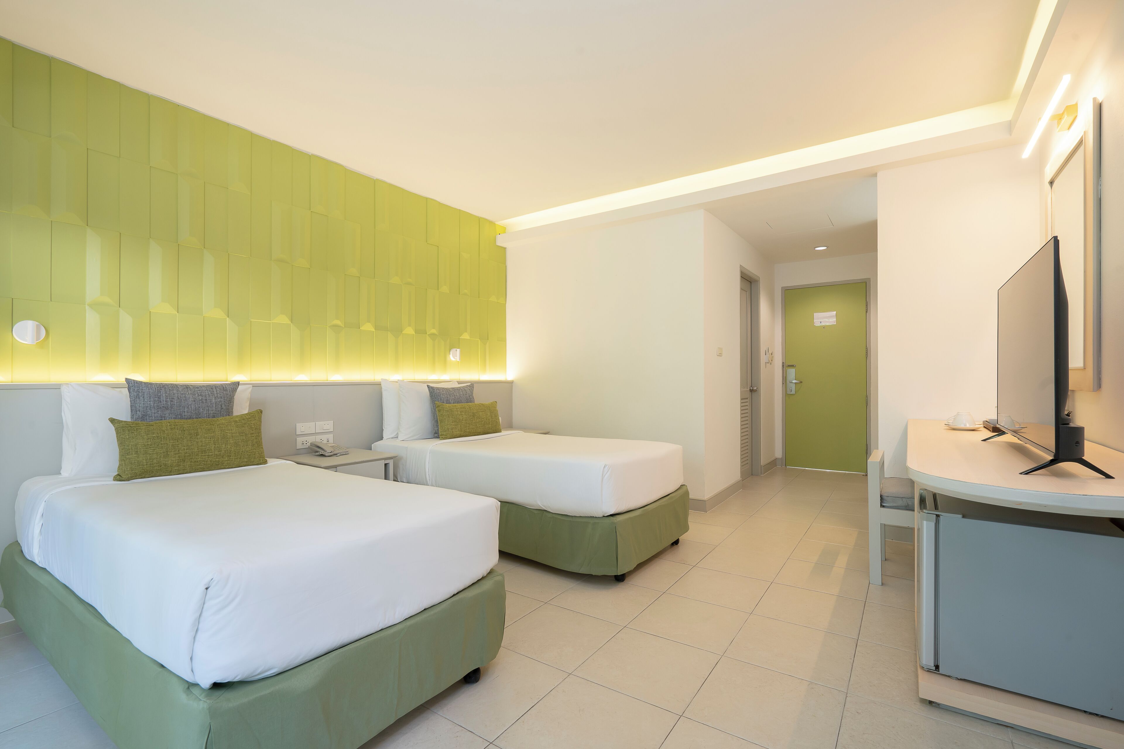 A hotel room with two beds, a desk, and a television.