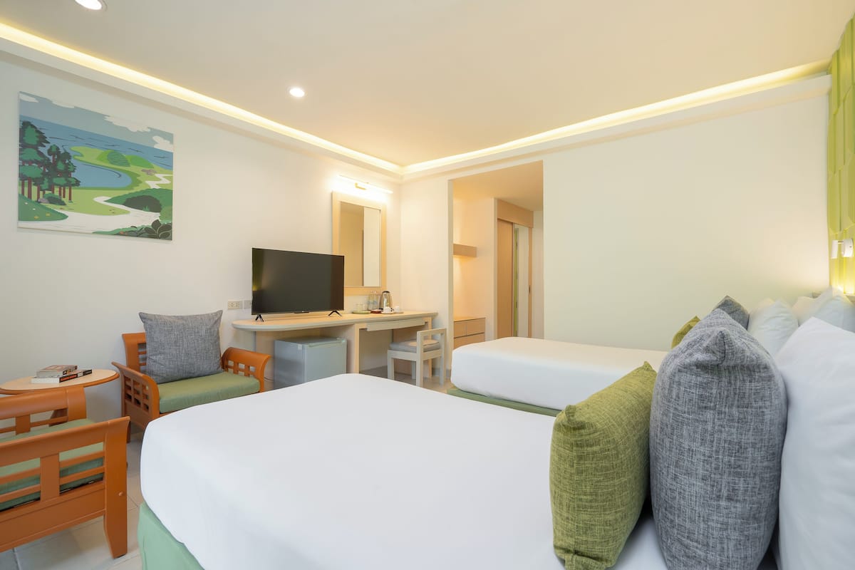 A hotel room with two beds, a desk, a chair, a TV, and a painting on the wall.