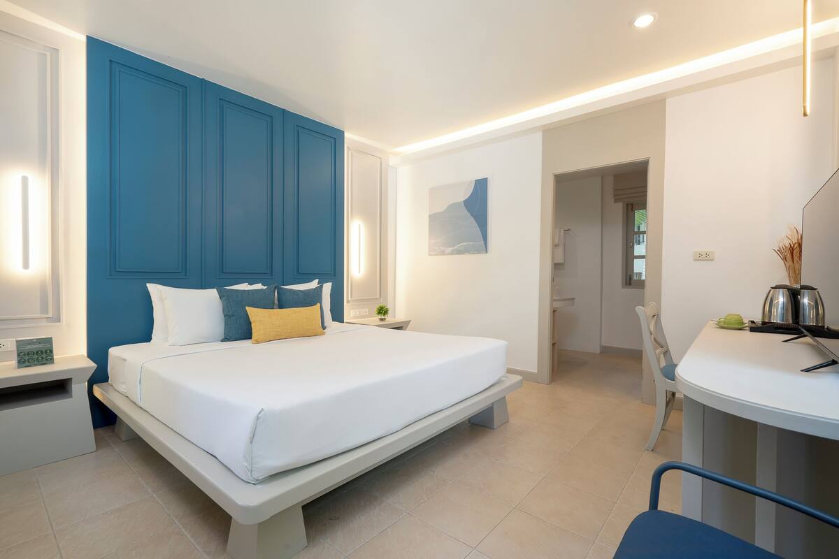 A modern bedroom with a large bed, bedside tables, a desk, and a chair.