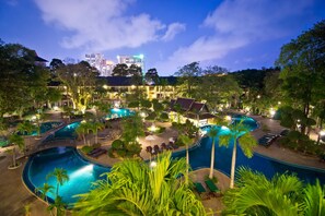 A resort with multiple swimming pools, palm trees, and a view of city buildings at night. - Green Park Resort (Pattaya)
