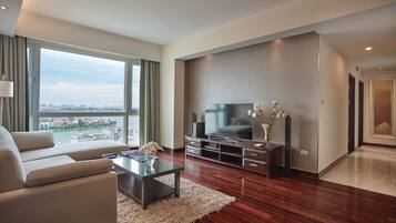 Una sala de estar moderna con un televisor grande, asientos cómodos, una mesa de centro de vidrio y vistas de la ciudad.