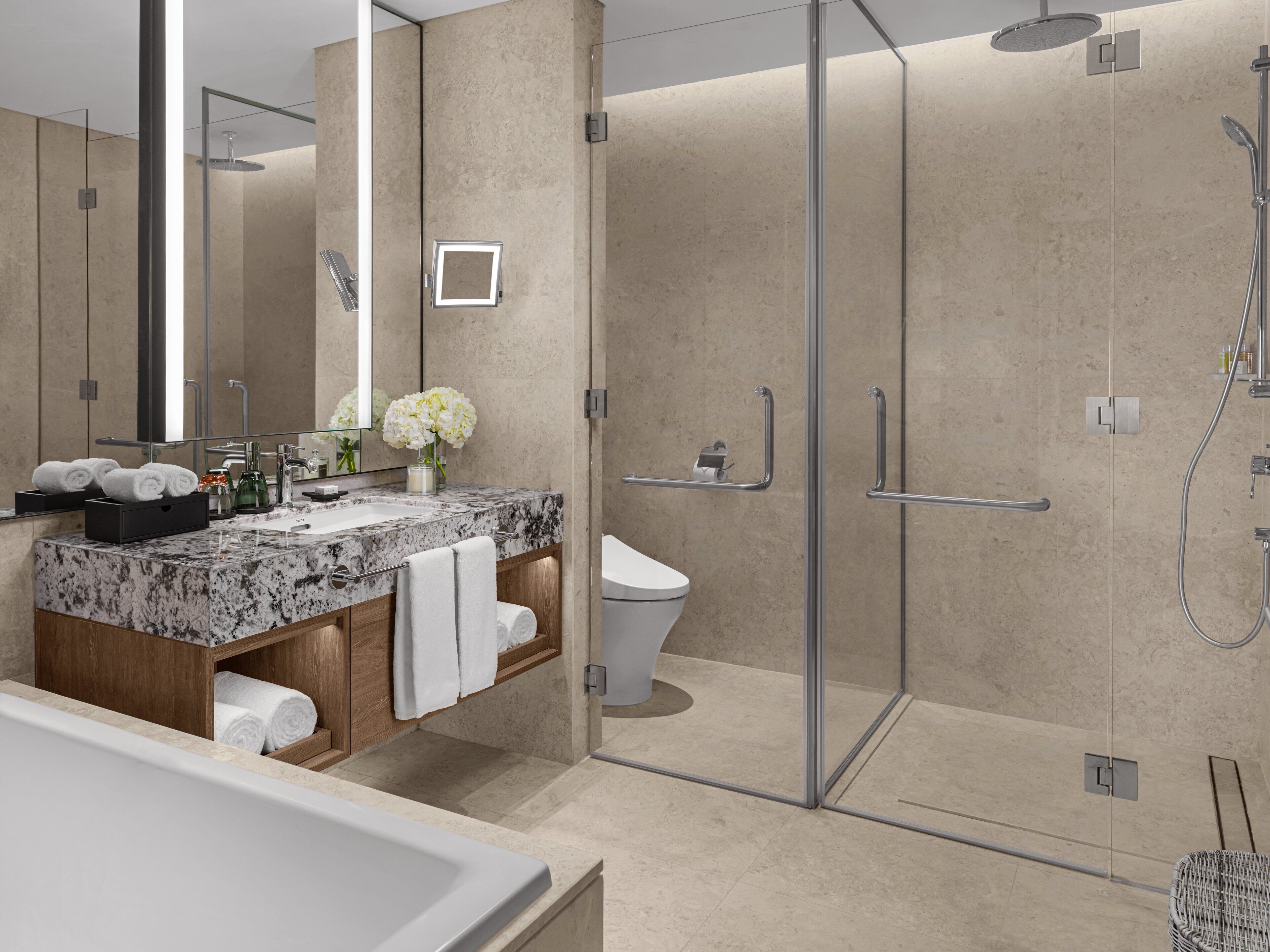 A modern bathroom with a glass-enclosed shower, a marble sink, and a toilet.