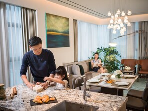 Una cocina moderna con encimera de mármol, un lavabo y una zona de comedor con una mesa dispuesta para dos personas.